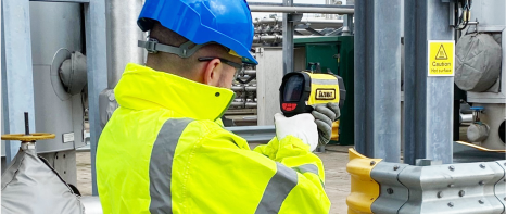 A picture of a safety official in high viz protective gearing using a hand-held Gazoscan unit to accurately determine gas concentrations from up to 330 feet away.