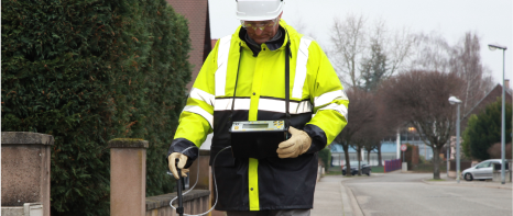 An image of a licensed professional in high viz PPE using an Inspectra portable optical detection device in the field.