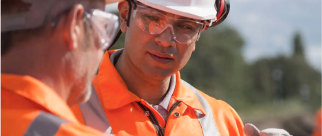 A picture of two men wearing hi-viz personal protective equipment in the field.