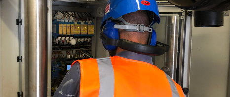 An image of a worker in the field wearing high-viz gear and PPE, installing an Ecotec Click! stationary gas monitor and analyzer. This compact, modular unit provides cost-effective and precise measurement and is endlessly upgradable depending on your industry needs.